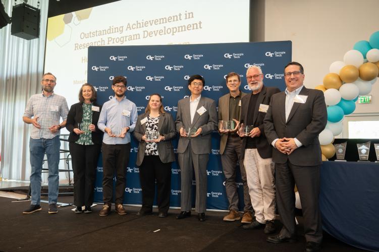 The Human Space Exploration research team smiles in front of a Georgia Tech background holding their awards on stage.